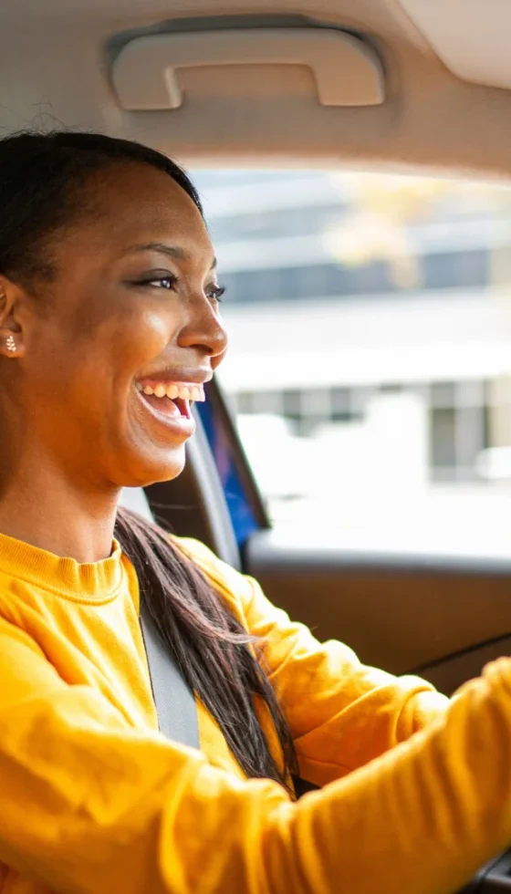 Happy young african american woman driving her car and smiling