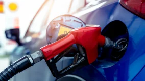 Blue car fueling up at gas station with red fuel nozzle at gas station