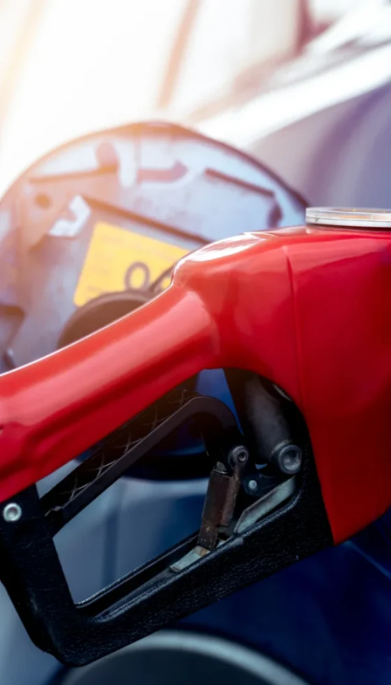 Blue car fueling up at gas station with red fuel nozzle at gas station