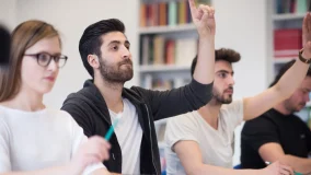 College classroom and group of students raising their hands