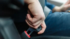 Male hand fastens the seat belt of the car from the driver's seat