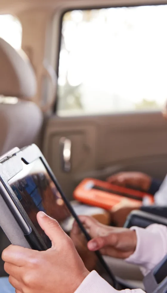 Mother turns around to see kids in their seat belts using tablets in the back of car