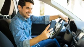 Young male driver in his car using his mobile phone