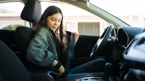 Teenage girl putting on her seatbelt getting ready to drive her car