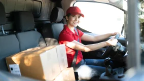 Commercial delivery woman driving behind the wheel and starting to make package deliveries in her van