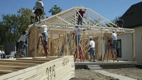 Volunteers helping to build new home and stacks of lumber out front