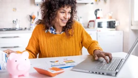 Cheerful woman comparing online website credit score and paper insurance policy statement