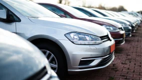 Several cars aligned in a row in a brick parking lot