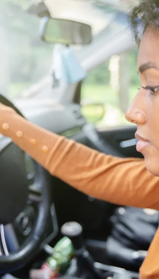 Young woman sitting in her car npt wearing a seat belt and checking her phone