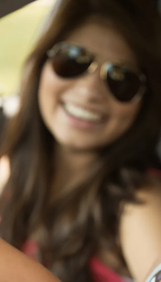 Young teenager and her friend having fun driving in the car wearing seat belts