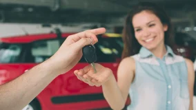 Young happy woman being handed a keyfob to her new car at a dealership