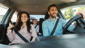 Happy mom, dad, and child traveling by car and wearing seat belts on road trip