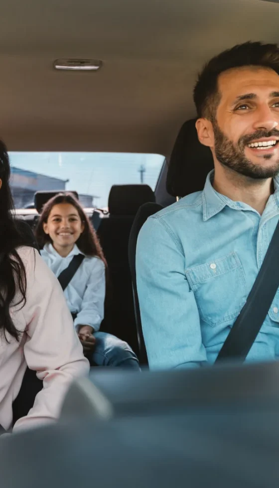 Happy mom, dad, and child traveling by car and wearing seat belts on road trip