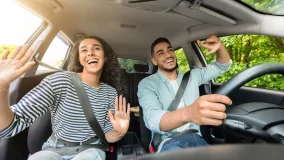 Smiling millennial couple having fun while driving their car on a road trip