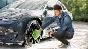 Young male caucasian taking the extra steps to keep his car clean by washing it and maintaining