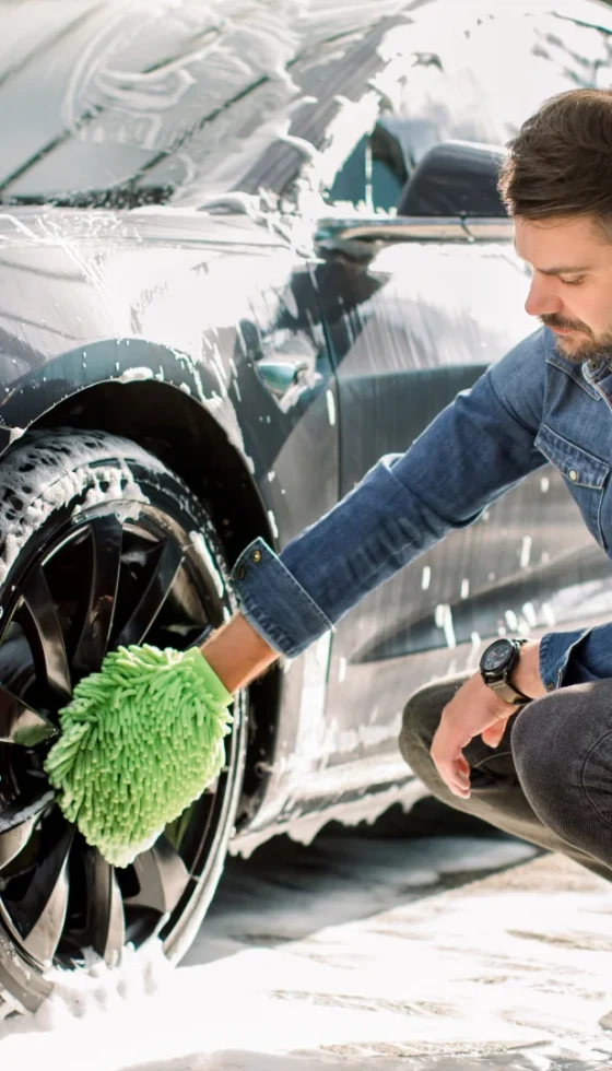 Young male caucasian taking the extra steps to keep his car clean by washing it and maintaining