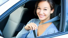 Young college girl in a car putting on her seat belt headed back to school