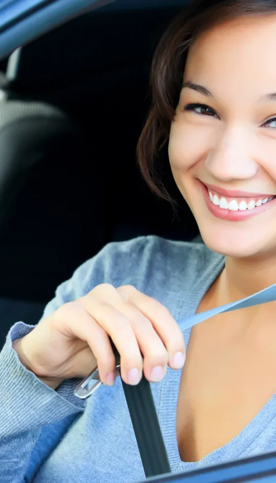 Young college girl in a car putting on her seat belt headed back to school