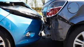 Blue and gray cars involved In rearend traffic accident with dented hood and bumper