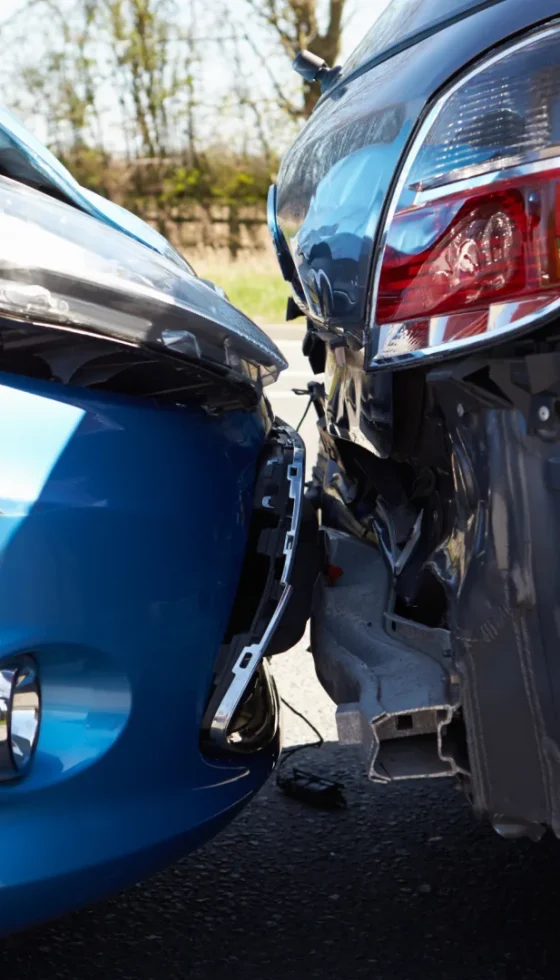 Blue and gray cars involved In rearend traffic accident with dented hood and bumper