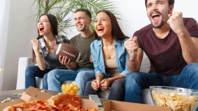 Group of friends hosting a football watching party on TV.