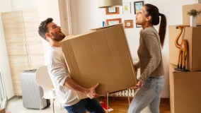 Young couple carrying cardboard box moving in together in new home