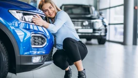 Young woman hugging the new car she bought in the showroom