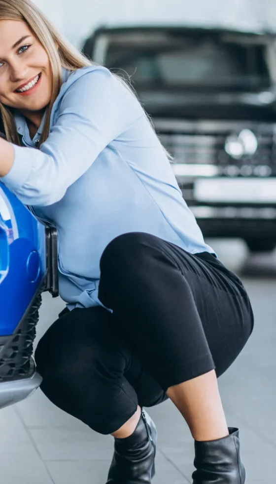 Young woman hugging the new car she bought in the showroom