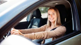 Woman safely driving a car wearing a seat belt with two hands on the steering wheel