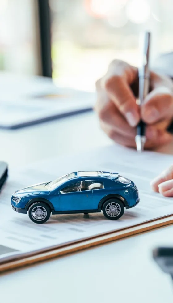 Man signing new car insurance document writing signature with car keys on table