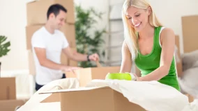 young couple unpacking moving boxes in a living room.