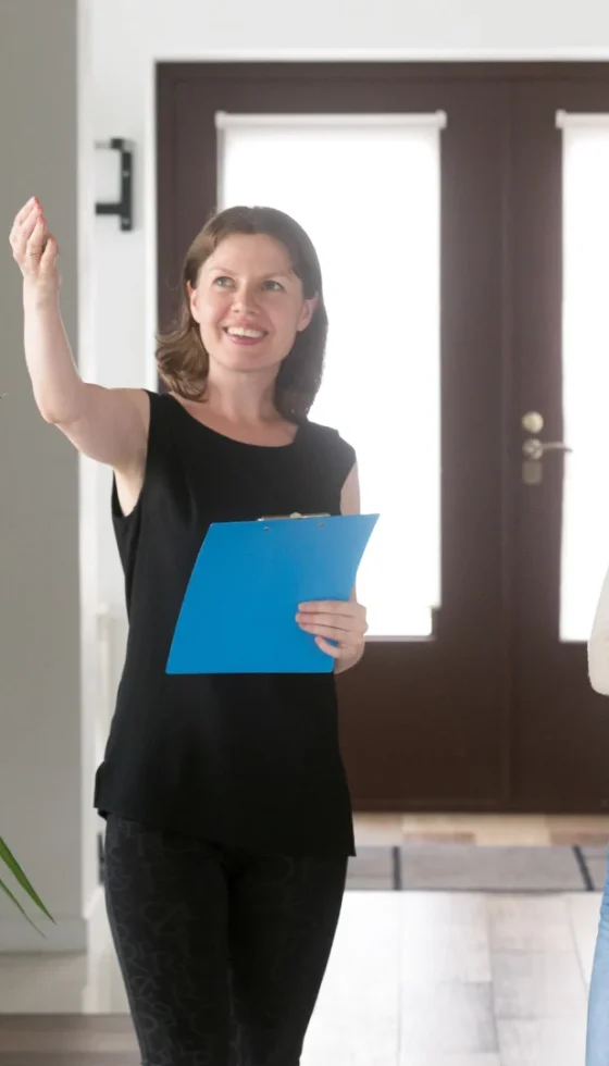 Smiling woman agent showing apartment for rent to young happy couple.