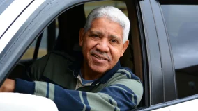 Senior man looking out the driver's side window of his new car and feeling happy