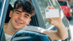 Teen driver looking out window in car with new driver's license