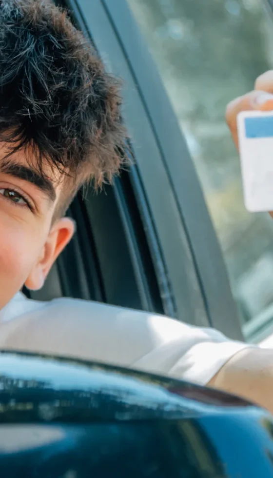 Teen driver looking out window in car with new driver's license