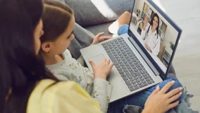 Family doctor online. Mom and little girl daughter are at home and use a video call to receive medical care online. Telemedicine concept.