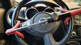 Closeup of car steering wheel with a red and black anti-theft security lock attached