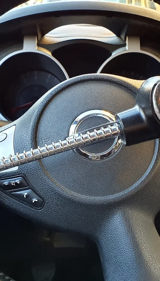 Closeup of car steering wheel with a red and black anti-theft security lock attached