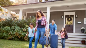 Family leaving house with luggage and traveling in their car for vacation