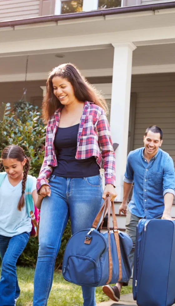 Family leaving house with luggage and traveling in their car for vacation