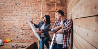 Couple looks at blueprints before starting a DIY home improvement project - cheap home insurance.