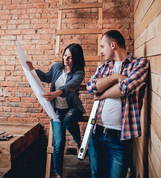 Couple looks at blueprints before starting a DIY home improvement project - cheap home insurance.