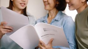 Group of women examine their home insurance policy - cheap homeowners insurance.