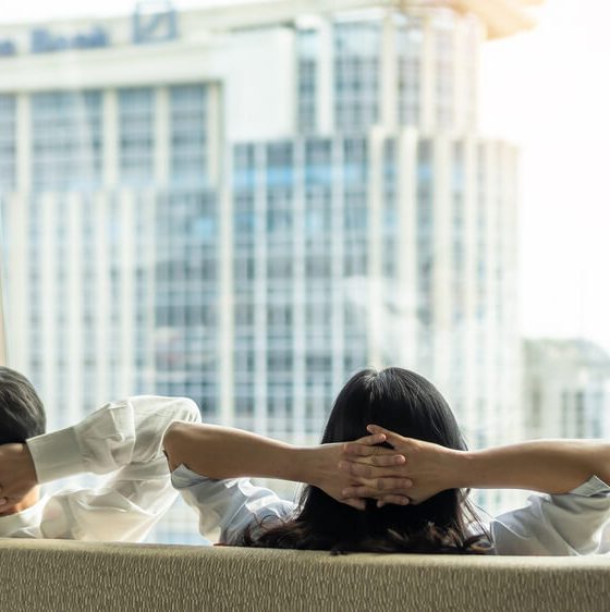Man and woman seen from behind relaxing on couch and looking out the window of their condo - cheap condo and home insurance.
