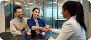 Young happy couple buying cheap car insurance with their insurance agent at a meeting in the office.