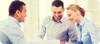 Smiling couple looking over types of cheap car insurance documents with insurance agent.