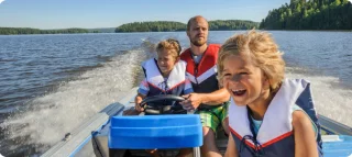 Family in life jackets on a boat on a lake.