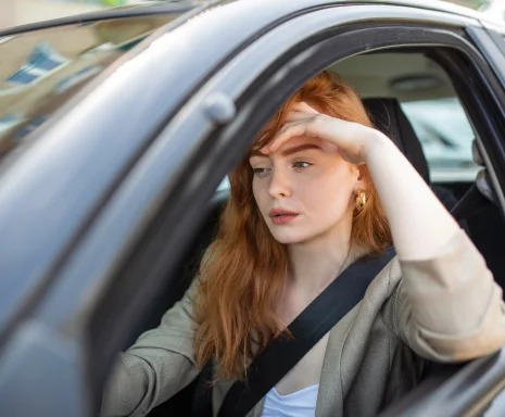 Young woman looking frustrated while driving a car