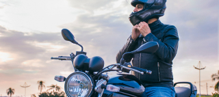 Man driving a motorcycle wearing a protective helmet