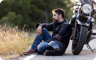 Man sitting next to broken down motorcycle